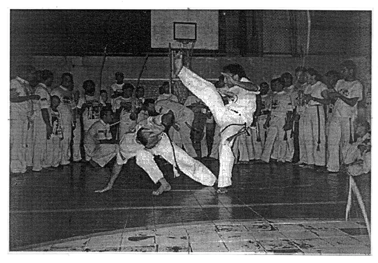 Capoeiristas jogando no centro da roda em um ginásio
